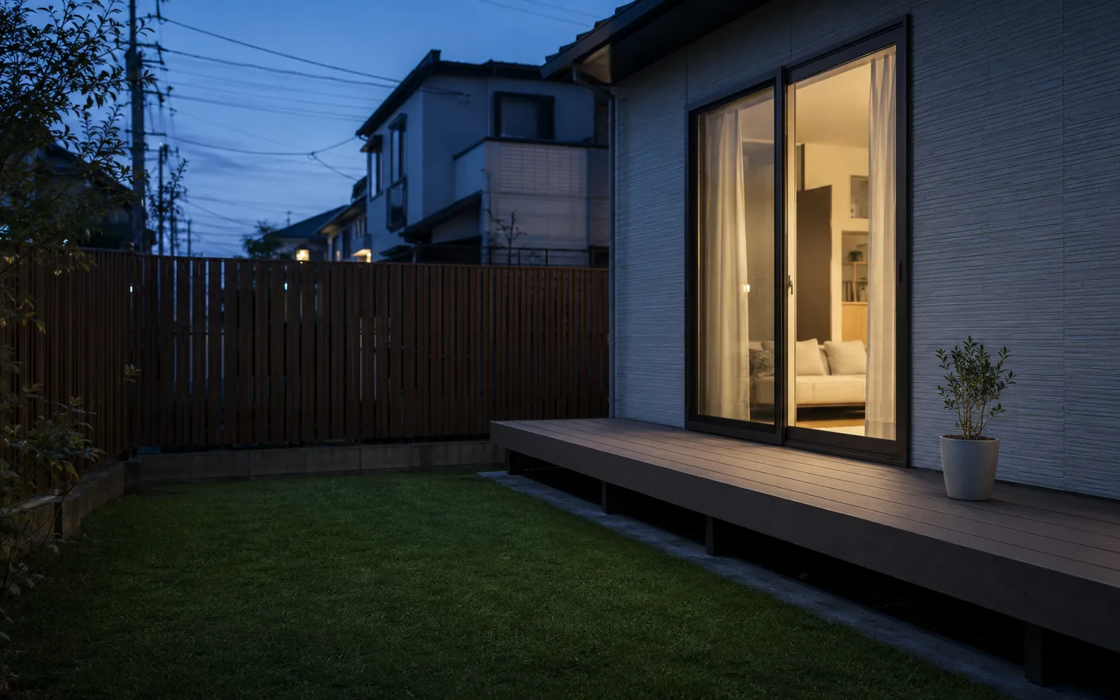夜のウッドデッキ。室内の灯りが芝生の庭までのびる